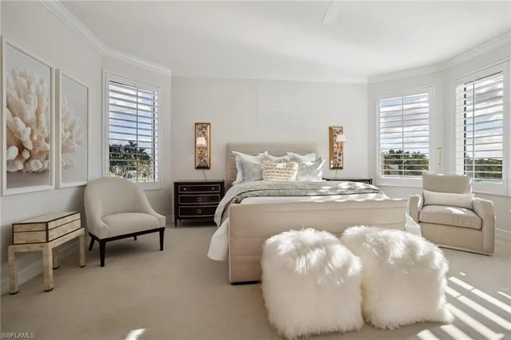 Carpeted bedroom featuring ornamental molding, multiple windows, and a ceiling fan