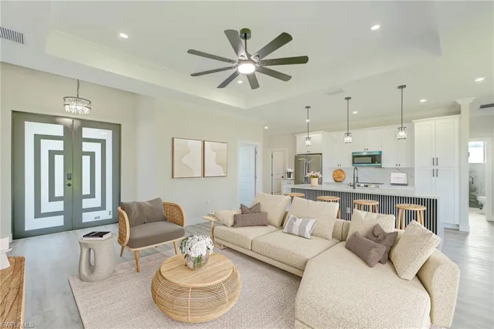 Kitchen featuring open floor plan, hanging light fixtures, a center island with sink, stainless steel appliances, and light countertops