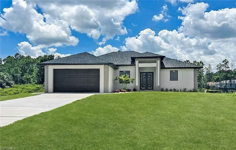 Prairie-style house featuring stucco siding, a front yard, a garage, concrete driveway, and roof with shingles