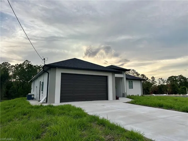 View of front of home featuring stucco siding, a garage, and driveway