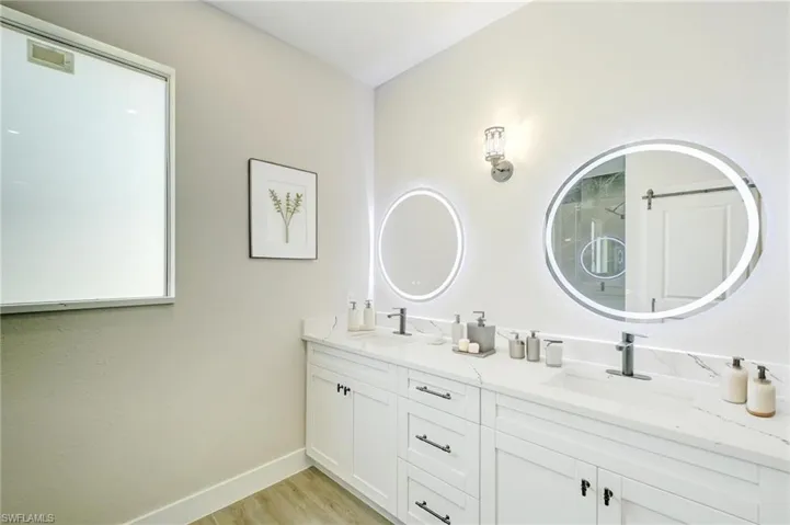 Kitchen featuring pendant lighting, stainless steel appliances, light stone counters, crown molding, and white cabinets