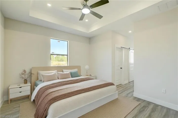 Virtual Stage -Kitchen with appliances with stainless steel finishes, light wood-type flooring, white cabinets, light stone countertops, and a breakfast bar area