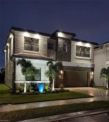 View of front of house featuring stone siding, stucco siding, an attached garage, and driveway