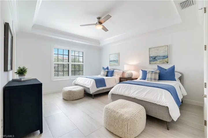 Bedroom with ceiling fan, ornamental molding, and a tray ceiling