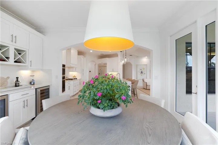 Dining space with ornamental molding, wine cooler, a dry bar, arched walkways, and recessed lighting