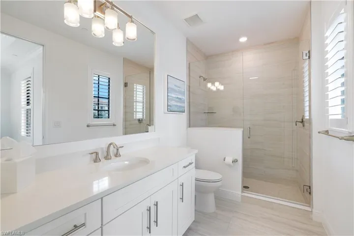 Bathroom featuring a shower stall, healthy amount of natural light, vanity, and hanging lights