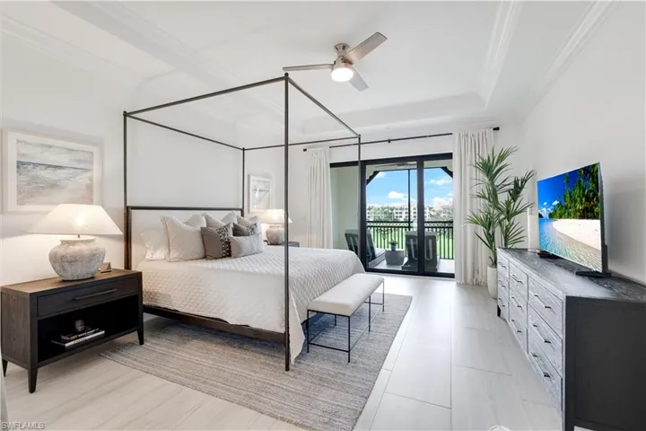 Bedroom featuring access to exterior, a ceiling fan, and a tray ceiling
