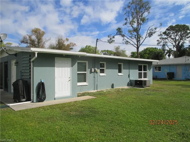 Rear view of property featuring a yard, central air condition unit, and stucco siding