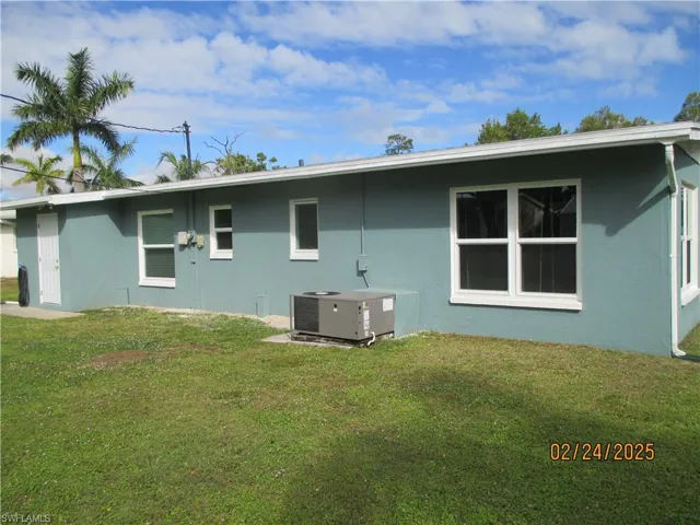 Back of property featuring a lawn, central AC, and stucco siding