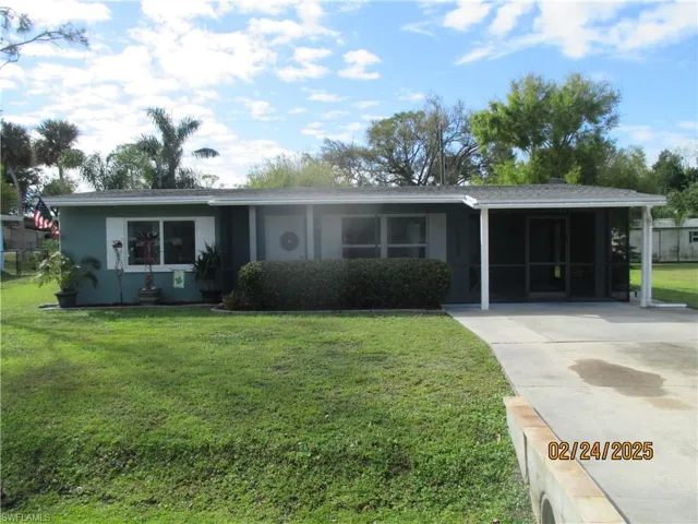 Single story home with driveway, an attached carport, and a front yard
