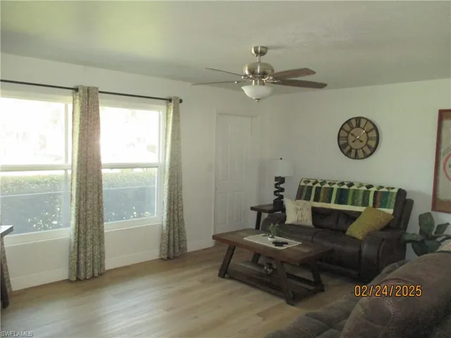Living room featuring light wood-type flooring, ceiling fan, and baseboards