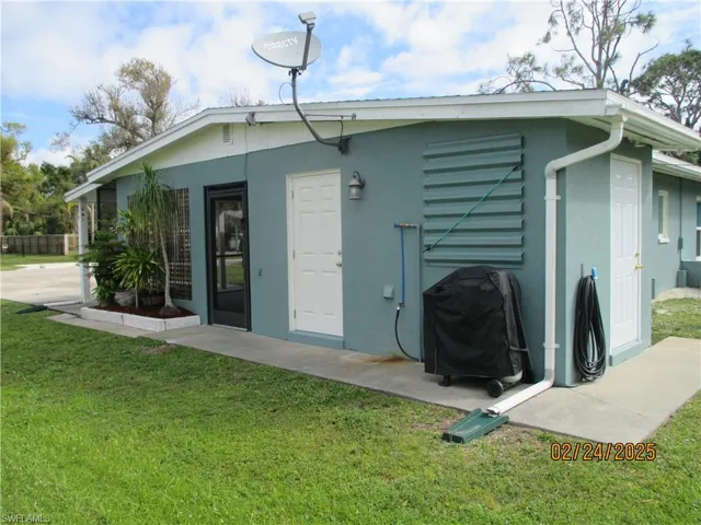 Back of house with a yard and stucco siding