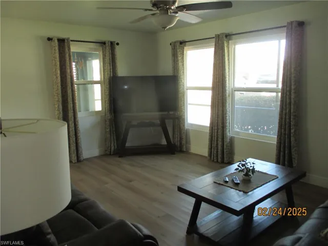 Living room featuring ceiling fan, wood finished floors, and baseboards