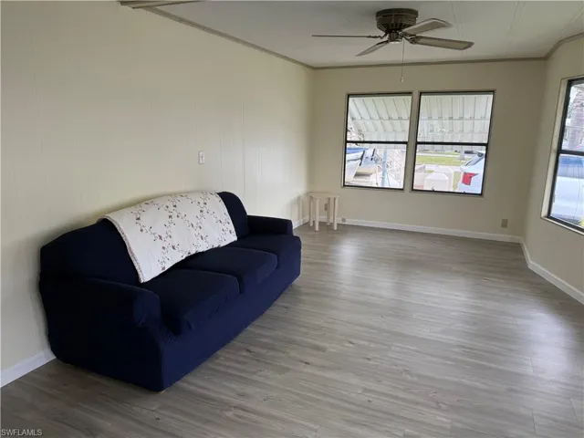 Living room featuring ceiling fan, light hardwood / wood-style flooring, and ornamental molding