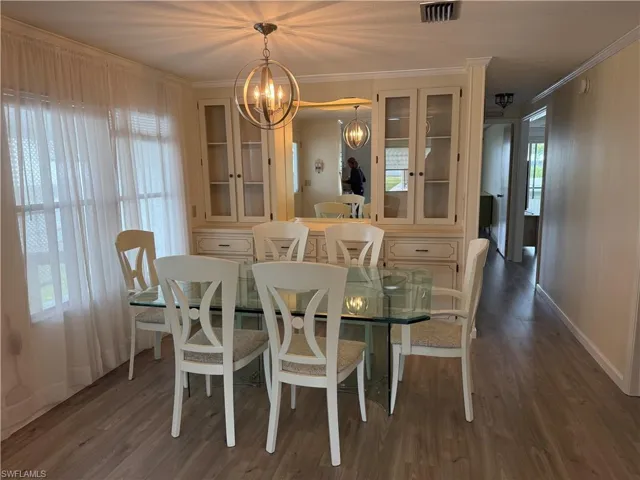 Dining area featuring dark hardwood / wood-style floors, crown molding, and a notable chandelier
