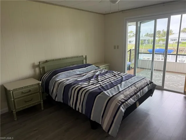 Bedroom featuring hardwood / wood-style floors, access to outside, multiple windows, and ceiling fan