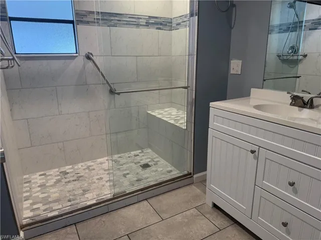 Bathroom with tile patterned floors, vanity, and walk in shower