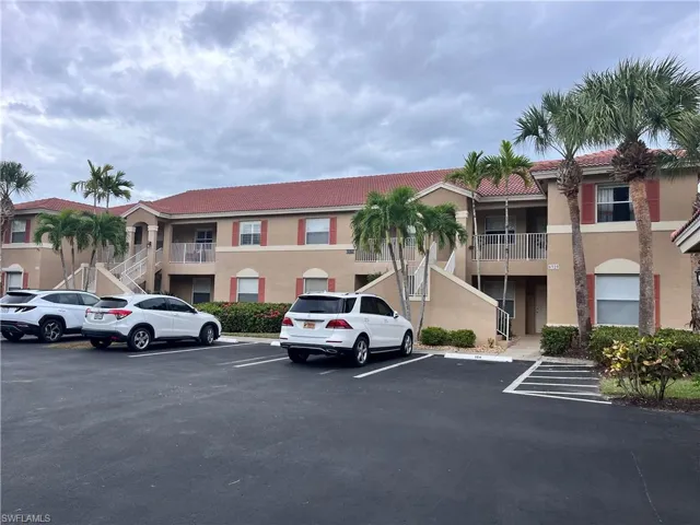 View of building exterior with one assigned parking spot located in front of the unit.