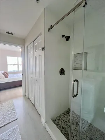 Ensuite bathroom with a closet, a shower stall, and light wood-style flooring