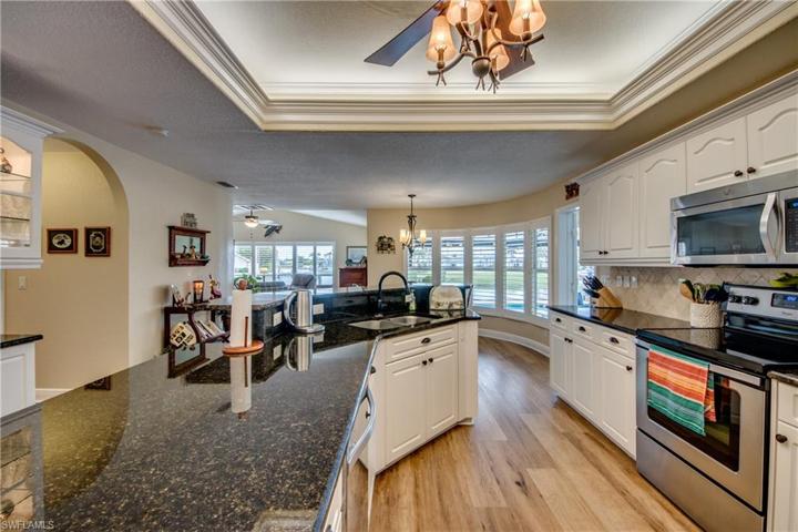 Beautiful kitchen with plenty of counter space, lighted tray ceiling, granite counters, tiled backsplash