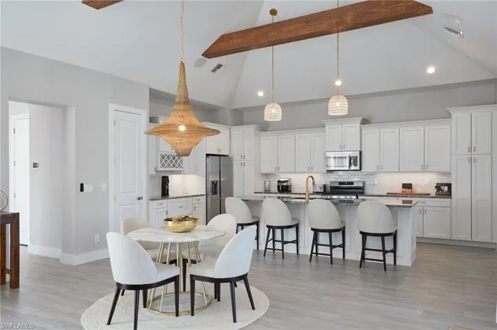 Dining space featuring light wood-type flooring, visible vents, beam ceiling, and high vaulted ceiling