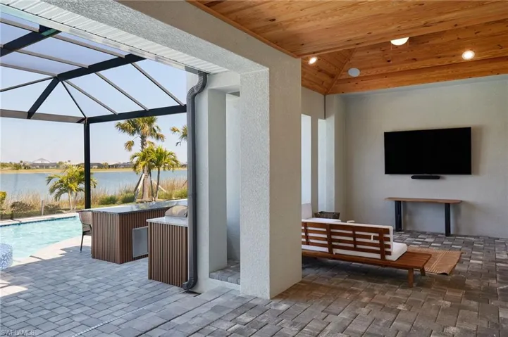 View of patio featuring an outdoor pool, glass enclosure, a water view, and an outdoor living space