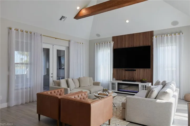 Living area featuring beam ceiling, plenty of natural light, visible vents, and light wood finished floors
