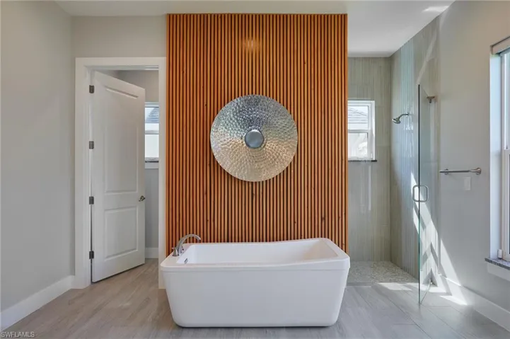 Full bath with a freestanding tub, baseboards, wood finished floors, and a shower stall
