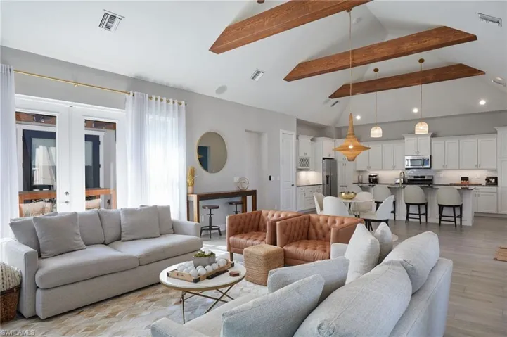 Living room featuring visible vents, beamed ceiling, and light wood finished floors
