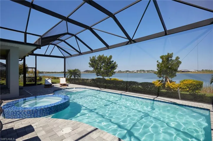 View of pool featuring a water view, a pool with connected hot tub, a lanai, and a patio area