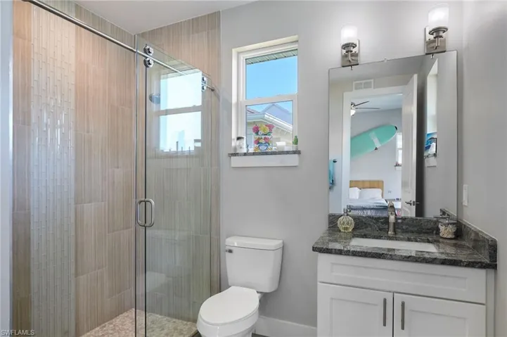 Bathroom with visible vents, a stall shower, ceiling fan, toilet, and connected bathroom
