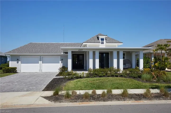 View of front facade with decorative driveway, a garage, and roof with shingles