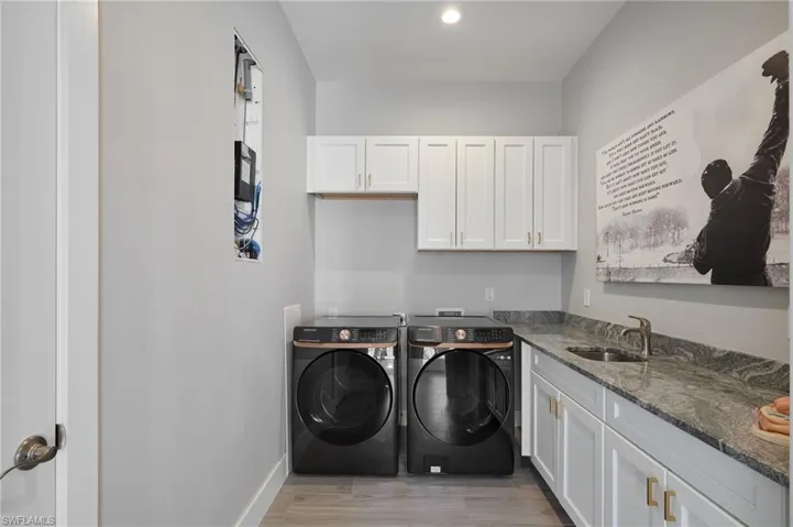 Laundry area with a sink, baseboards, light wood-style flooring, cabinet space, and separate washer and dryer