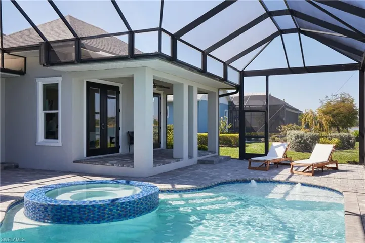View of swimming pool featuring glass enclosure, a patio, a pool with connected hot tub, ceiling fan, and french doors