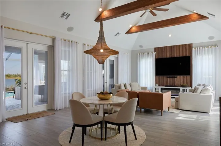 Dining room featuring french doors, beam ceiling, light wood-style floors, and visible vents