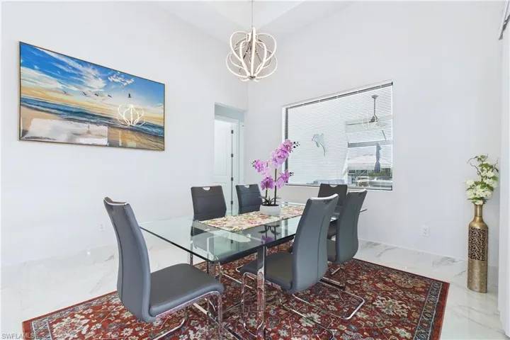 Dining space with marble finish flooring, a chandelier, and a high ceiling