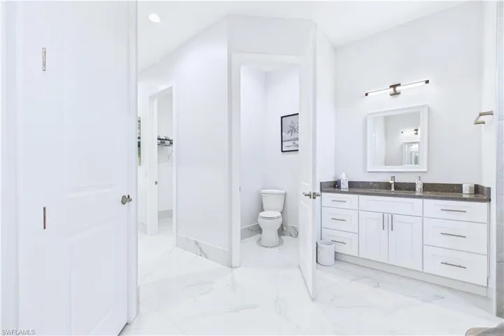Bathroom with vanity, light marble finish floors, and recessed lighting