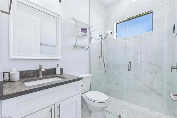 Full bathroom featuring a marble finish shower and vanity