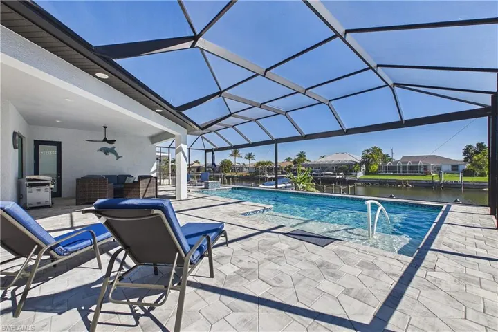 Swimming pool with a patio, glass enclosure, a sunroom, area for grilling, and a residential view