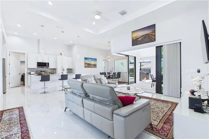 Living room with a raised ceiling, ceiling fan, and recessed lighting