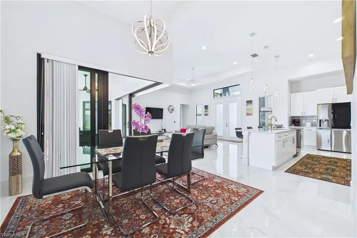 Dining room with a high ceiling, a chandelier, ceiling fan, and light marble finish floors