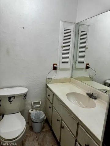 Half bathroom featuring vanity and a textured wall