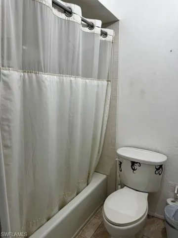 Bathroom featuring shower / bath combo, tile patterned floors, and a textured wall