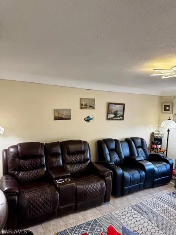 Living room with a ceiling fan and a textured ceiling