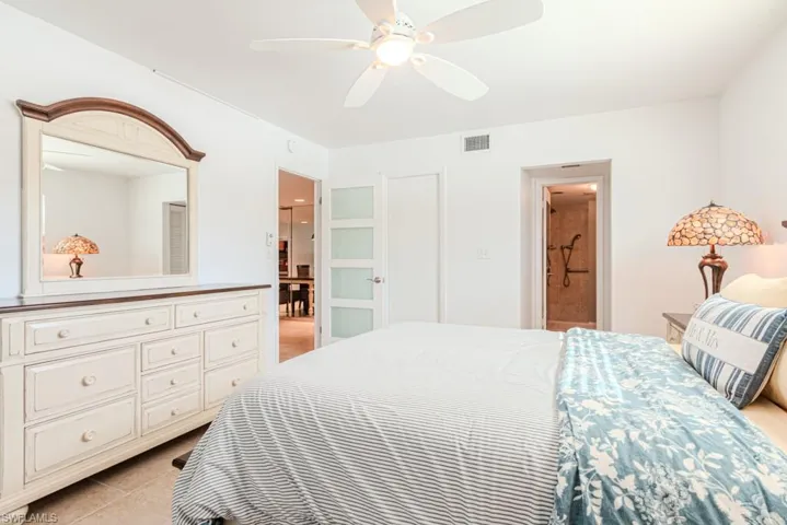 Bedroom with ceiling fan, light tile patterned floors, and connected bathroom