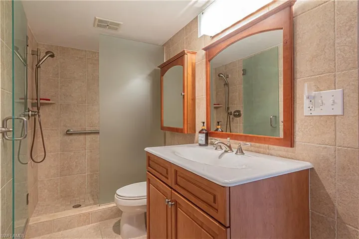Full bathroom with a shower stall, vanity, light tile patterned floors, and tile walls