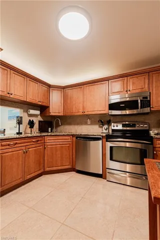 Kitchen with stainless steel appliances, light stone countertops, and wood finish cabinets