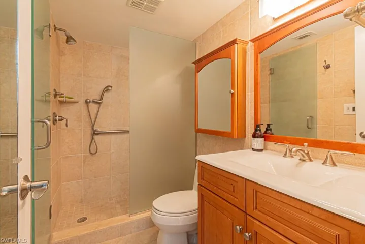 Full bathroom featuring vanity, a stall shower, and tile walls