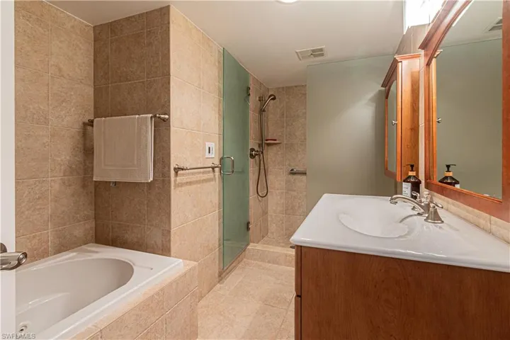 Full bathroom with a stall shower, a garden tub, vanity, and light tile patterned floors