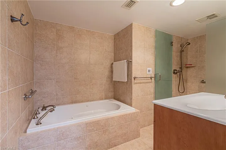 Full bathroom featuring a stall shower, vanity, tile walls, a garden tub, and tile patterned flooring
